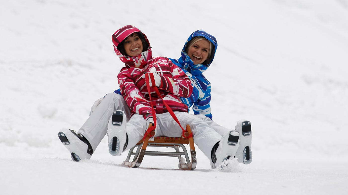 Zwei Freunde auf einem Schlitten in der Nähe unseres Hotels direkt an der Skipiste Sellaronda