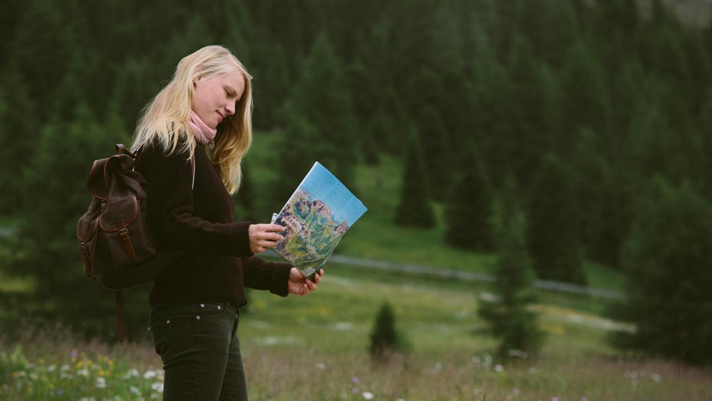 Ein Mädchen im Wald studiert die Wanderkarte des Sellaronda