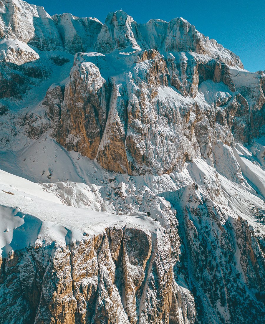 Pareti rocciose imponenti delle Dolomiti ricoperte di neve sotto un cielo limpido.