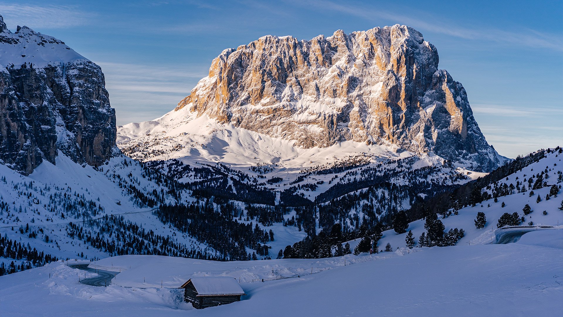 Veduta aerea dello Chalet Gerard e della strada a tornanti del passo, immersi nei boschi ai piedi delle maestose Dolomiti