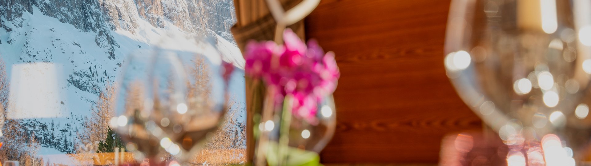 View from the restaurant with blurred wine glasses in the foreground and snowy mountains in the background.